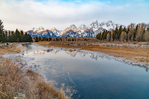 Reflection on the Snake river of the Teton peaks of Grand Teton National Park in Wyoming, western USA. Nearest town is Jackson, Wyoming.