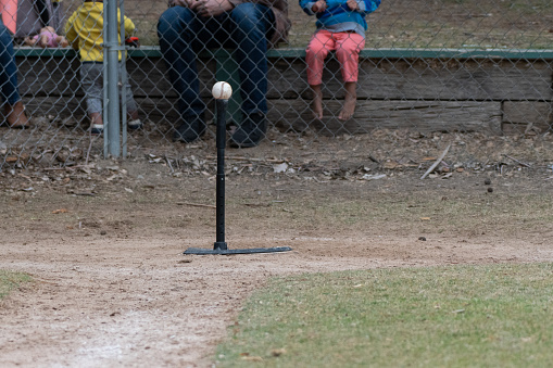 Batting tee set up on home plate with baseball resting on top for the next batter.