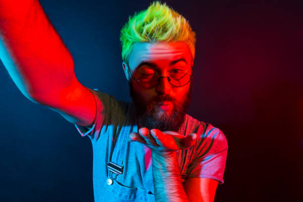 istock Romantic bearded hipster man with beard in denim overalls talking via web camera with girlfriend, expressing love, broadcasting live stream. 1317322311
