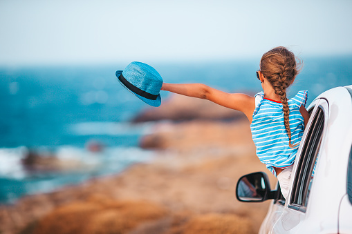 Back view of girl with hat on vacation by car