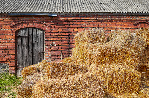 Golden haystack in front of an old brick building.