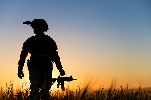 Soldier walking in battlefield at sunset
