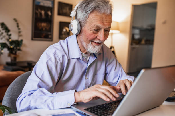 istock Senior man sitting at the desk at home and using laptop 1317330994