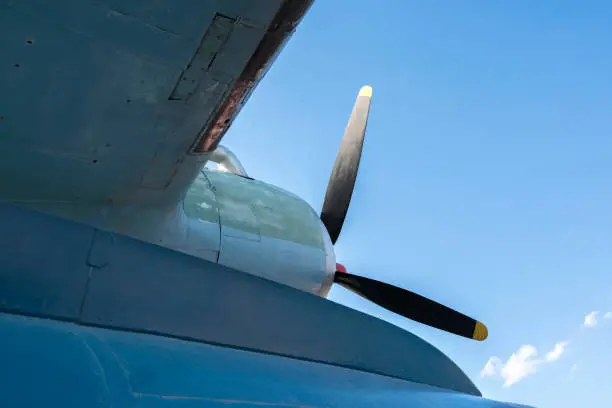 Photo of The rusty military plane close up against the background of clouds and the blue sky.