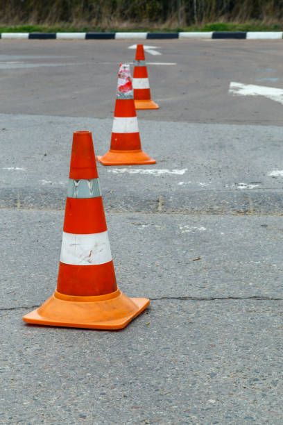 istock orange traffic cones on dry gray asphalt road surface - close-up with selective focus 1317332994