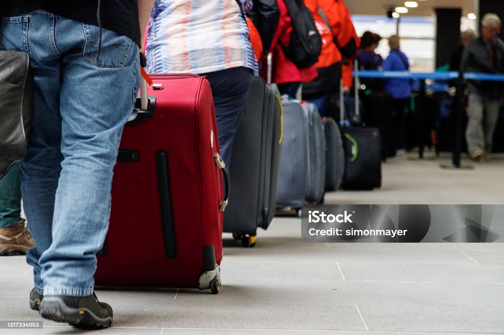 Group of people with luggage lining up at an airport check-in counter Emigration and Immigration Stock Photo