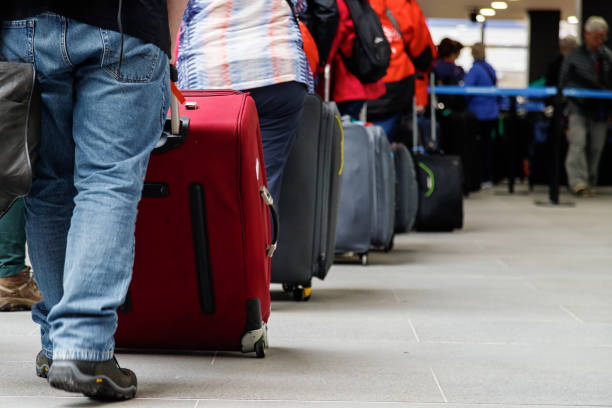 Group of people with luggage lining up at an airport check-in counter stock photo