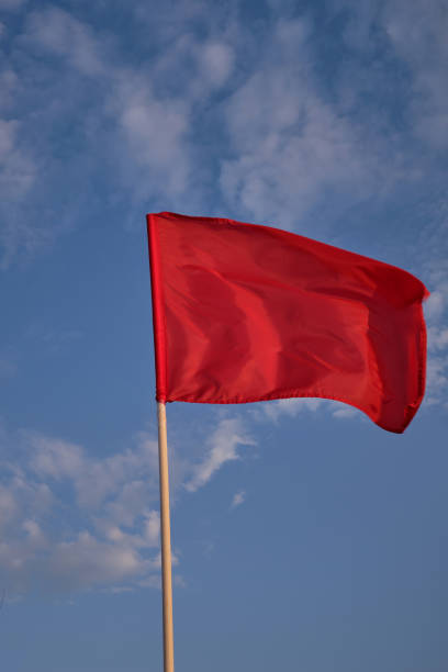 istock Red flag with blue sky with clouds, strong wind flying red flag. Red flag warning flags 1317334543