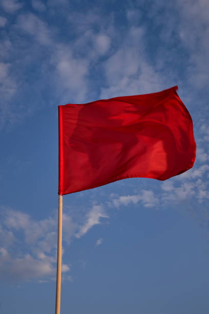 istock Red flag with blue sky with clouds, strong wind flying red flag. Red flag warning flags 1317334572