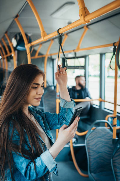 istock Woman using a smartphone and standing by herself on a bus 1317337209