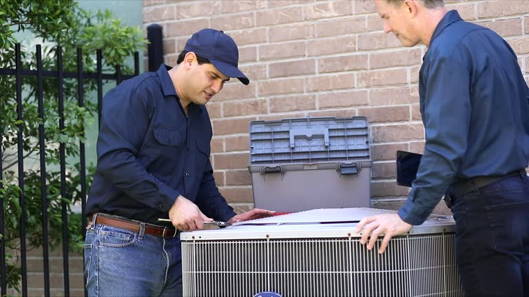 Multi-ethnic team of blue collar air conditioner repairmen at work.