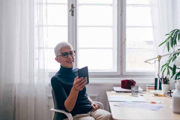 istock Smiling Senior Businesswoman Using her Mobile Phone at Work 1317338156