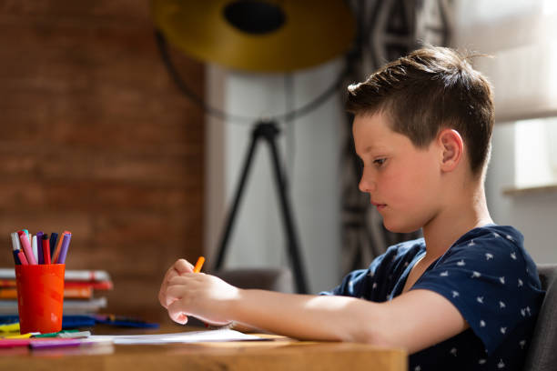 istock Boy sitting at the table and writing homework. 1317339108
