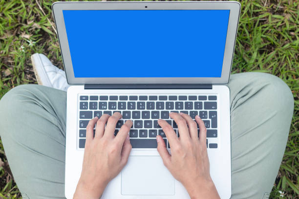 Lady`s Hands typing on a Laptop with a Blue Screen. Outdoors and new normal concept