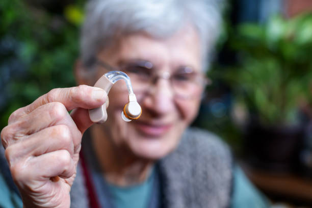 sorrindo idosa segurando um aparelho auditivo - hearing aid isolated technology healthcare and medicine - fotografias e filmes do acervo