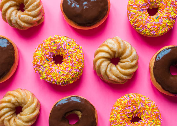 istock Overhead of assorted donuts against a bright pink background. 1317348997