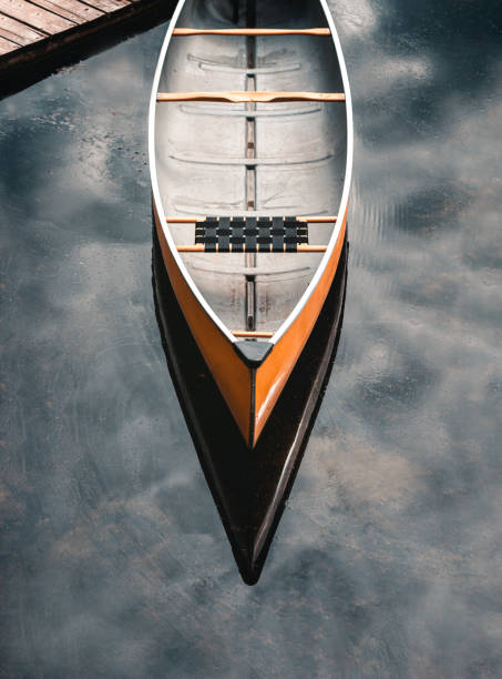 Overhead image of empty yellow canoe on mottled blue water. in Kingston, ON, Canada
