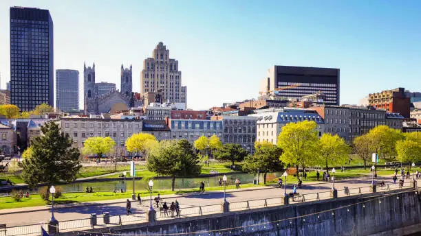 Vieux port de Montreal and downtown skyline with promenade pier on a clear May Springtime day with people walking in the distance