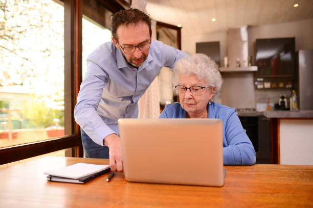 istock mature man helping elderly senior woman at home with paperwork and computer internet lesson 1317361767
