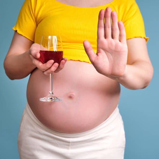 alcohol in the hands of a pregnant woman on a blue background - eastern european caucasian one person alcoholism imagens e fotografias de stock