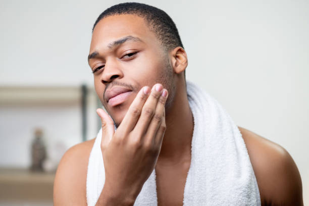 hombre acicalando el cuidado de la piel hombre africano tocando la cara - male towel men human face fotografías e imágenes de stock