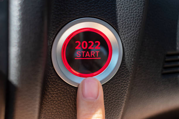 premi un pulsante di accensione dell'auto con testo start 2022 all'interno della moderna automobile elettrica. capodanno new you, risoluzione, cambiamento, obiettivo, visione, innovazione e concetto di pianificazione - beginnings car engine ignition foto e immagini stock