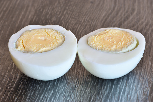 Side view of a boiled chicken egg cut in half. Both halves lie yolks up next to each other.
