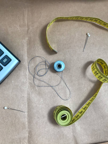 istock Calculator, yellow centimeter and bobbin with threads on a brown background 1317381509