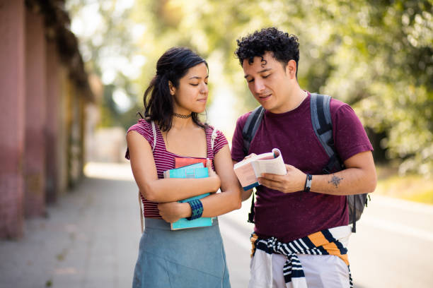 istock Two young students standing on street with books and talking.  Reading book. 1317382301