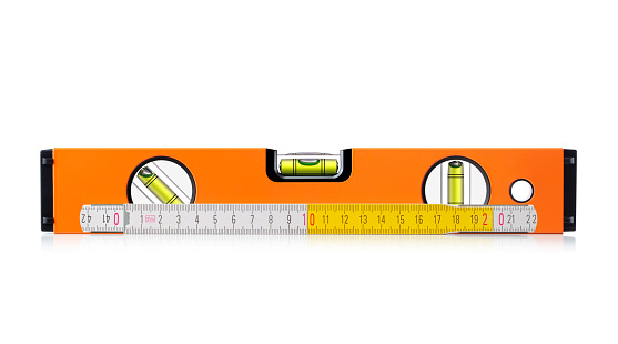 Construction bubble level and yellow and white wooden folding ruler isolated on white background.