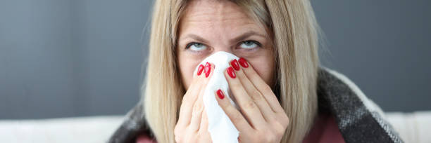 istock Sick woman blows her nose into handkerchief. 1317384338