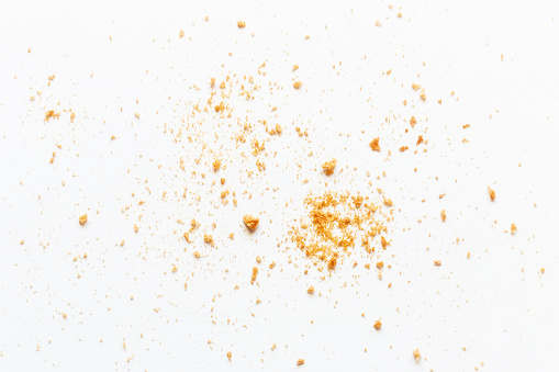 scattered crumbs of roasted white bread on a white background closeup