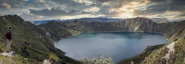istock Caucasian backpacker looking at a marvelous lake inside a volcano named Quilotoa at sunset. Ecuador, 1317389637