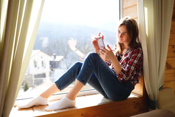 istock young girl talking on the phone while sitting by the window 1317390868