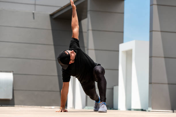 Fit sports man warming up with spider lunge exercise outdoors on building rooftop floor Fit sports man warming up with spider lunge exercise outdoors on building rooftop floor apple core stock pictures, royalty-free photos & images