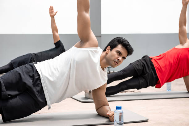 athletische indische mann tun seitenplanke übung im freien auf dem dach mit freunden - core strength stock-fotos und bilder