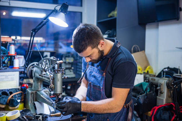 istock Young man in crafts shop preparing sewing machine for shoe repairs 1317391177