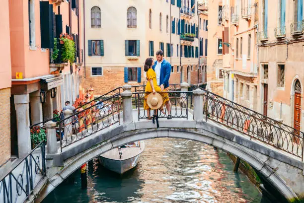 couple standing on the bridge crossing venice canals romantic city tourism