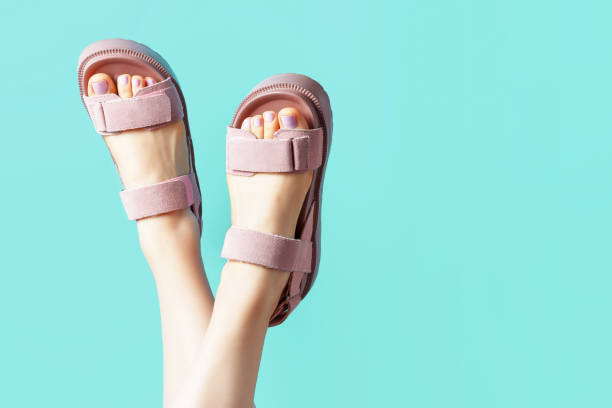 patas femeninas en sandalias rosas al revés sobre fondo azul. - zapato de plataforma fotografías e imágenes de stock