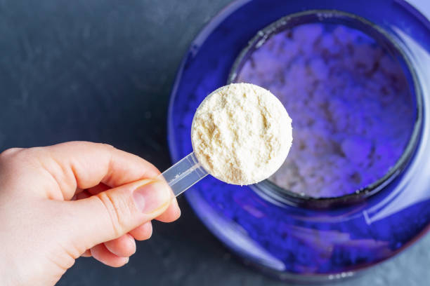 Scoop with protein in female hand top view, gray background