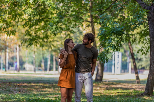 Portrait of Cheerful Young Couple who is Hugging Each Other in the Park Path and Having a Nice Conversation and Sweet Emotions.