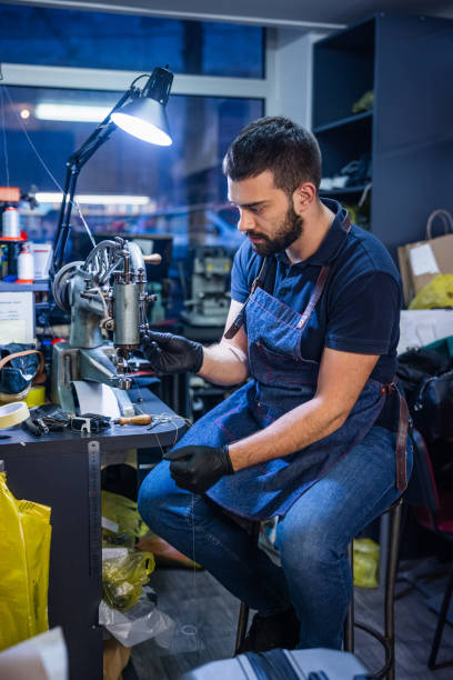 istock Young man in crafts shop threading sewing machine for shoe repairs 1317395155