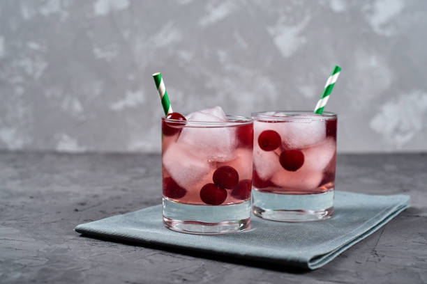 istock Fresh cherry lemonade with ice, mint and paper straw in sparkling glasses on gray table background, copy space. Cold summer drink. Berry cocktail 1317396504
