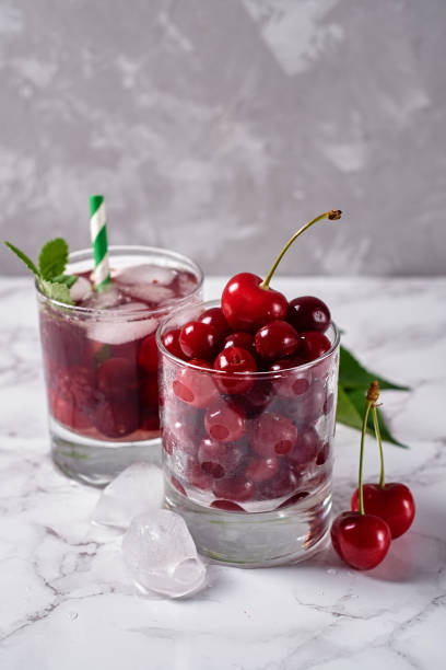 istock Fresh cherry lemonade with ice, mint and paper straw in sparkling glasses on table, copy space. Cold summer drink. Berry cocktail 1317396529