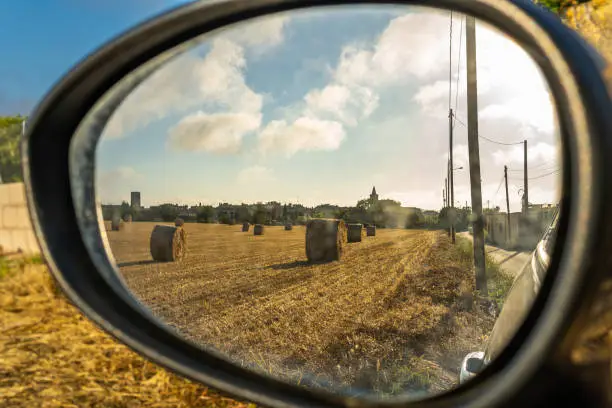 Straw balls in a rural field as seen through the rearviewmirror of a car in the Majorcan town of Porreres at dawn