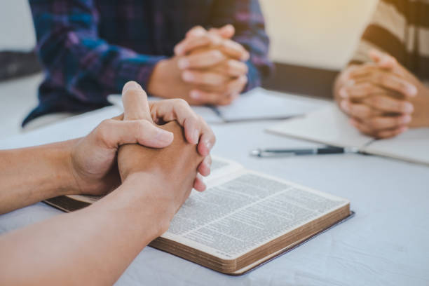istock christian small group praying together and open bible to read. 1317397881