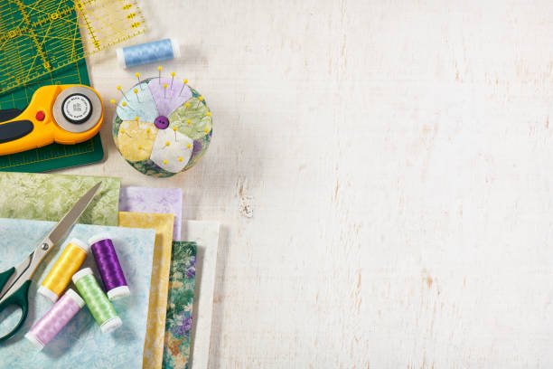 istock Pincushion, stack of fabrics, sewing and quilting accessories lying on a cutting mat, space for text 1317402286