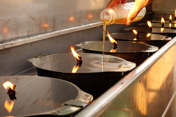 hand is pouring oil into lamp to make a wish,add oil to lamp,buddhist merit making,make merit for temple thailand - oil lantern imagens e fotografias de stock