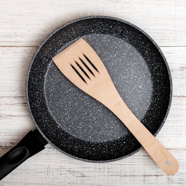istock Frying pan with non-stick ceramic coating and spatula on a white wooden background. Cooking without sticking or oil. 1317403789