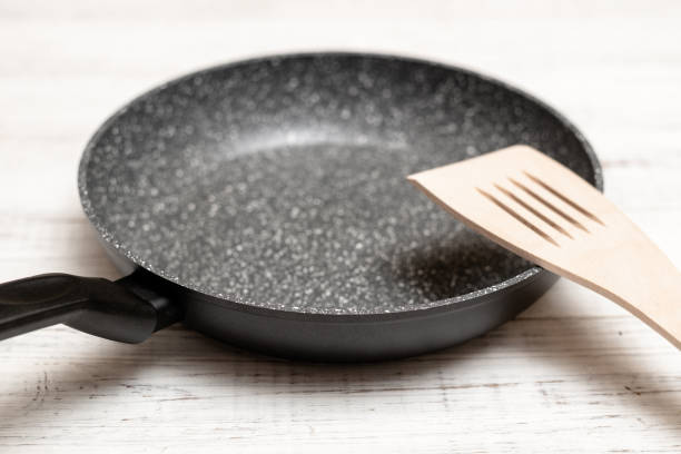 istock Frying pan with non-stick ceramic coating and spatula on a white wooden background. Cooking without sticking or oil. 1317403803